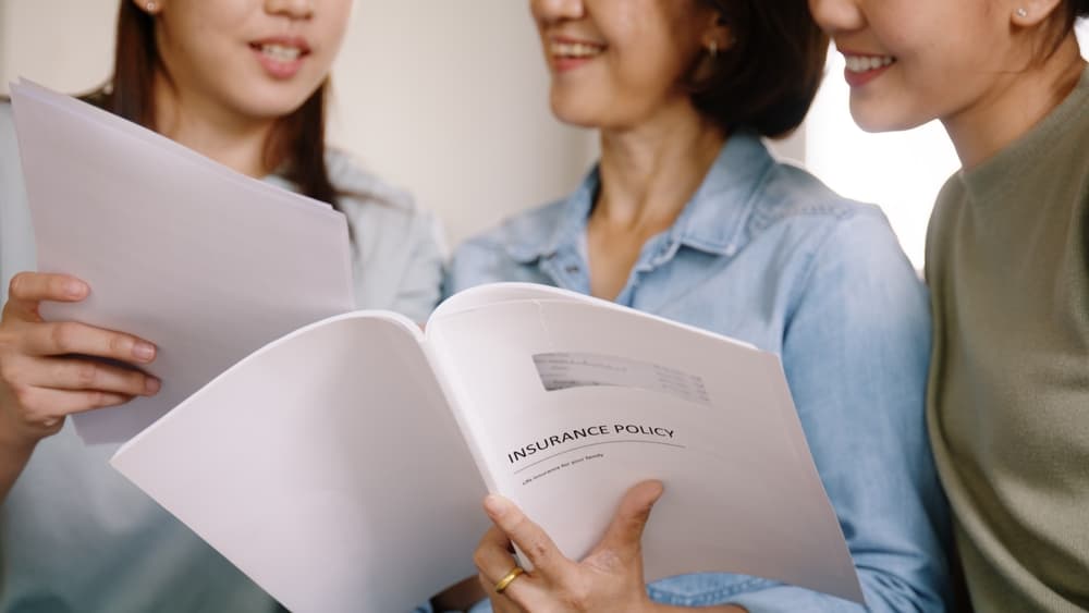 women-smiling-and-reading-insurance-policy